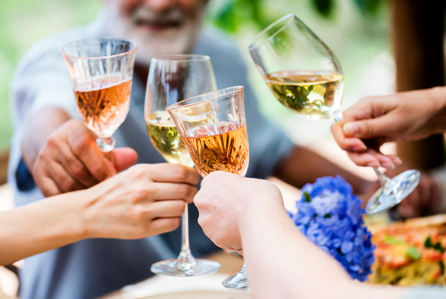 Group of people cheers over beverages from outdoor kitchen bar cart.